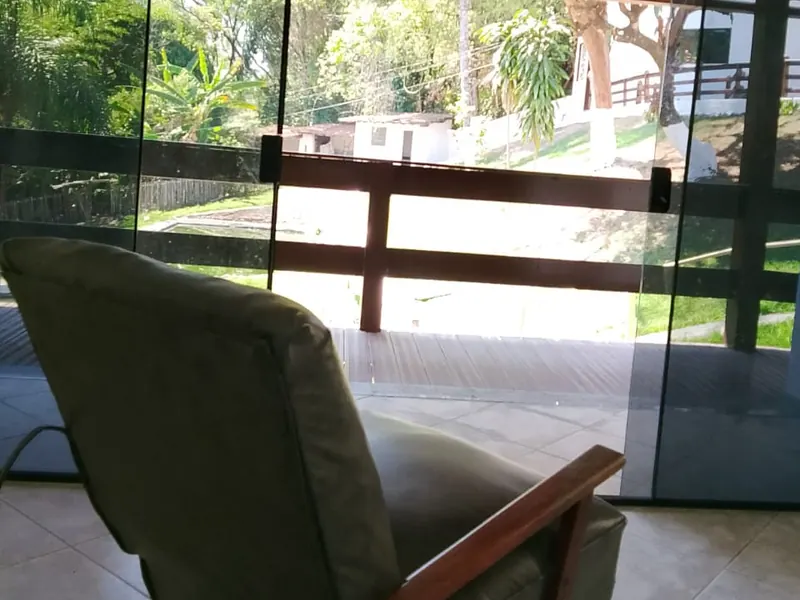 Poltrona de tecido junto a uma parede de vidro com vista para a área externa